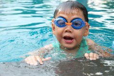 Kind am Beckenrand Kind mit Schwimmbrille am Beckenrand