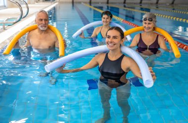 Vier Menschen bei Wassergymnastik mit bunten Poolnoodles