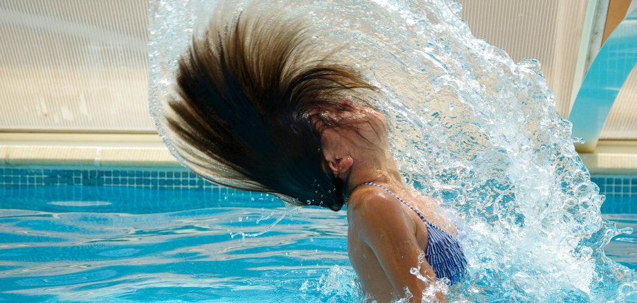 Frau taucht aus dem Wasser auf Haare spritzen