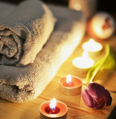 Handtücher mit angezündeten Kerzen und Blüte