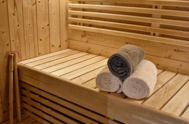Drei Handtücher gerollt auf Saunabank